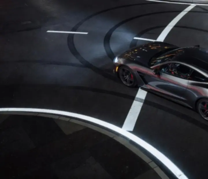 Trajectoire lumineuse d'une voiture de nuit tracée sur une route urbaine